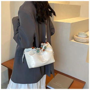 Detail of cream cloud bucket bag with croc-effect texture and colorful beaded strap