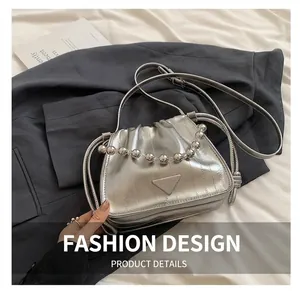 Detailed view of silver pleated bucket bag with beaded handle and metal logo on fabric
