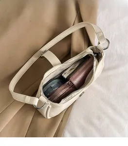 Draufsicht auf cremeweiße Leder-Achseltasche mit Platz für Kosmetik im Innenraum