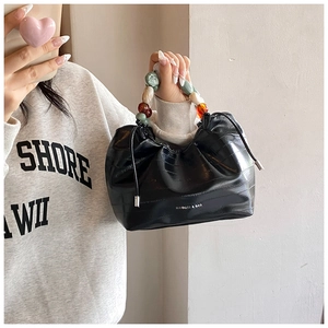 Detail of black faux leather bucket bag with crocodile texture and colorful resin beads