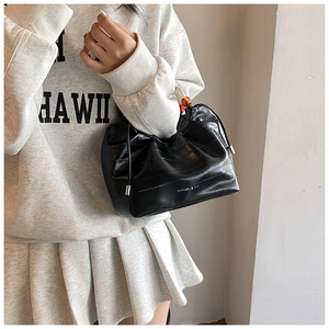 Detail of black faux crocodile leather bucket bag with amber and cream beaded handle decoration
