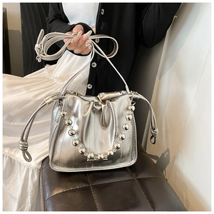 Detail of silver metallic drawstring bucket bag with beaded handle and vertical texture