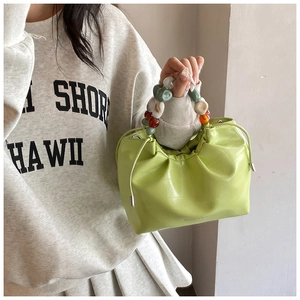 Detail of lime green bucket bag with crocodile texture and colorful beaded handle