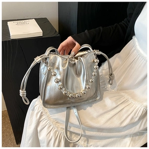 Detail of silver drawstring bucket bag featuring a chic beaded chain and metallic finish