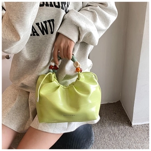 Detail of bright green crocodile texture bucket bag with colorful beaded handle