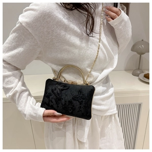 Detail of black evening bag with 3D butterfly embroidery and gold metal handle