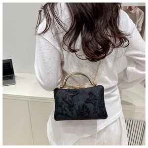 Detail of elegant black evening bag with 3D butterfly embroidery and gold metal handle