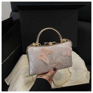 Detail view of pink butterfly embroidery evening bag with gold chain in a black gift box