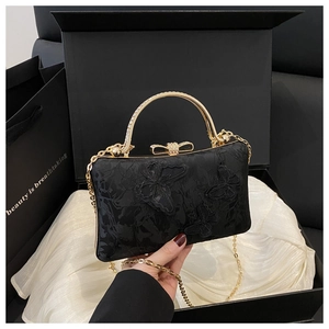 Detail of black evening bag with butterfly embroidery and rhinestone handle in a gift box