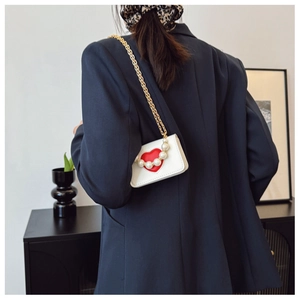 Detalle de mini bolso de cuero blanco con corazón rojo y ribete de perlas en la solapa