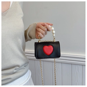 Primer plano de mini bolso negro con corazón rojo en relieve y asa de perlas elegante