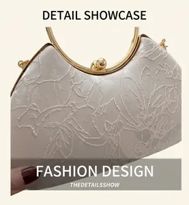 Close-up of floral embroidery on elegant beige evening bag with golden ring handle