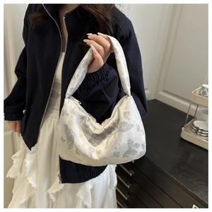 Vue détaillée de la broderie papillon argentée sur le sac à bandoulière en satin ivoire
