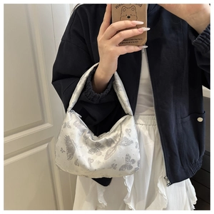 Détail de la broderie papillon argentée sur un sac hobo en forme de croissant au fini soyeux