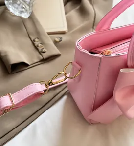 Detail der rosa Handtasche mit großer Schleife und polierten goldfarbenen Metallbeschlägen