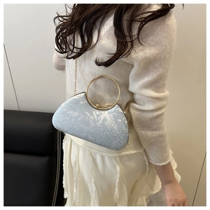 Detail of evening clutch with lace texture, golden ring handle and chain strap