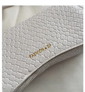Detail of white woven leather texture with gold Fashion & Bags logo on minimalist bag