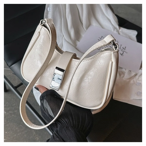 Detail einer cremefarbenen Kunstleder-Schultertasche mit silbernem Metall-Magnetverschluss