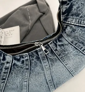 Detail van soepele zilveren metalen rits en gestikt denim op retro gewassen handtas