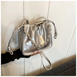 Close-up of metallic silver drawstring bucket bag with textured folds and bead chain