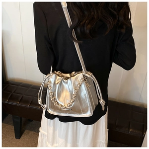 Detail of silver metallic bucket bag with drawstring closure and beaded handle