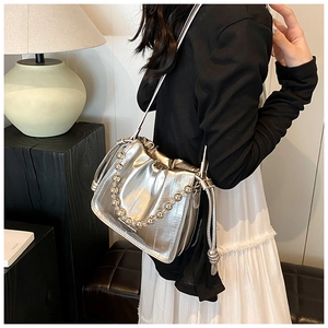 Detail of silver pleated bucket bag with metallic bead chain and leather shoulder strap