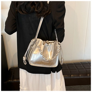 Close-up of silver bucket bag with metallic texture, drawstring detail, and bead chain strap