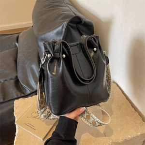 Glänzende schwarze Lederbeuteltasche mit buntem Jacquard Schultergurt im Trend