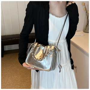 Close-up of metallic silver drawstring bucket bag with triangular metal logo and bead chain