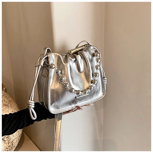Detailed close-up of metallic silver drawstring bucket bag with bead chain and logo