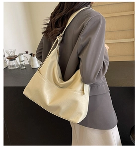 Close-up of a large beige hobo bag showing textured faux leather and zip pocket detail