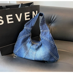 Detail van vintage denim hobo tas met contraststiksels en gewassen denim afwerking