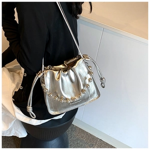 Detail of silver metallic bucket bag featuring a decorative clear beaded chain strap