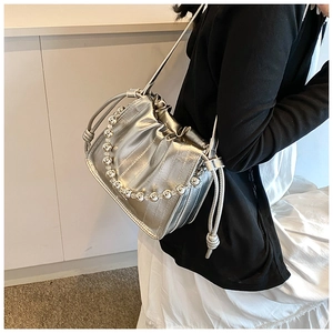 Detail of silver metallic drawstring bucket bag with beaded handle on model's shoulder
