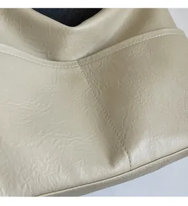 Detail of soft cream leather texture and precise stitching on large casual tote bag
