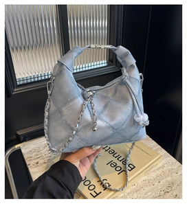 Detail of light blue denim dumpling bag with quilted pattern and braided top handle