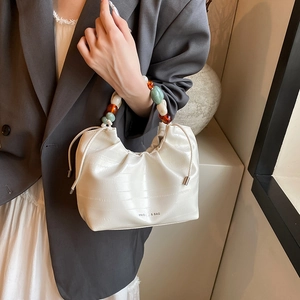 Cream drawstring bucket bag with colorful beaded handle and crocodile embossed leather