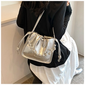 Detail of silver metallic drawstring bucket bag with large bead handle and fold design