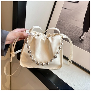 Detail of cream drawstring bucket bag with decorative silver beaded chain handle
