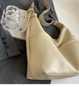 Detail of off-white pleated tote bag showing side pocket and adjustable strap
