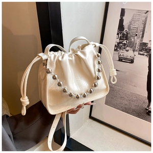 Detail of white drawstring bucket bag with crocodile texture and silver bead handle
