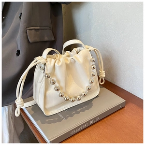 Detail of cream drawstring bucket bag with elegant pearl chain and textured leather
