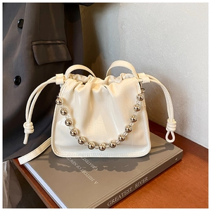 Detail of cream white bucket bag with crocodile texture and silver beaded handle