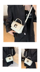 Détail d'un petit sac en cuir crème avec poignée à billes argentées et fermoir carré