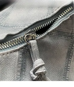 Detail of light blue denim texture fabric with a silver metal zipper and knotted puller