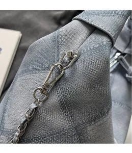 Detailed shot of light blue textured fabric with silver metal hooks and chain strap