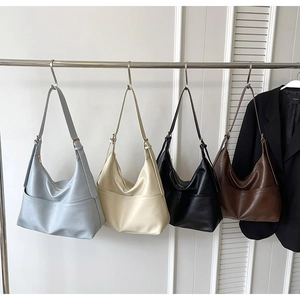 Detail view of large faux leather hobo bags in blue, white, black, and brown colors
