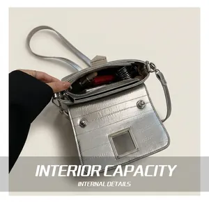 Vue intérieure du sac argenté motif crocodile montrant le compartiment et la poche zippée
