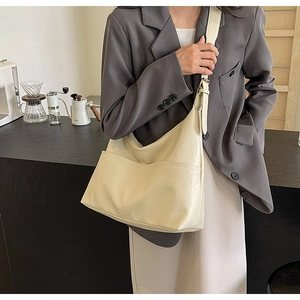 Creamy white large leather tote bag with front pocket and adjustable strap on a model