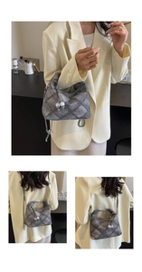 Detail of grey quilted dumpling bag with white ball charms and metal chain strap